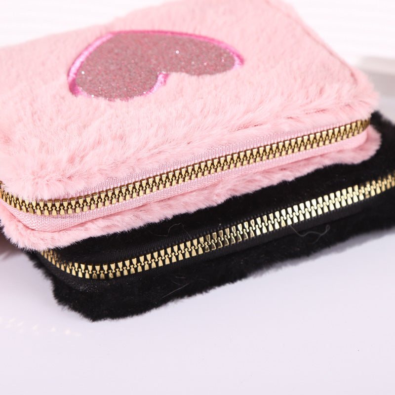 Porte-monnaie en peluche avec fermeture éclair brodée de cœur.