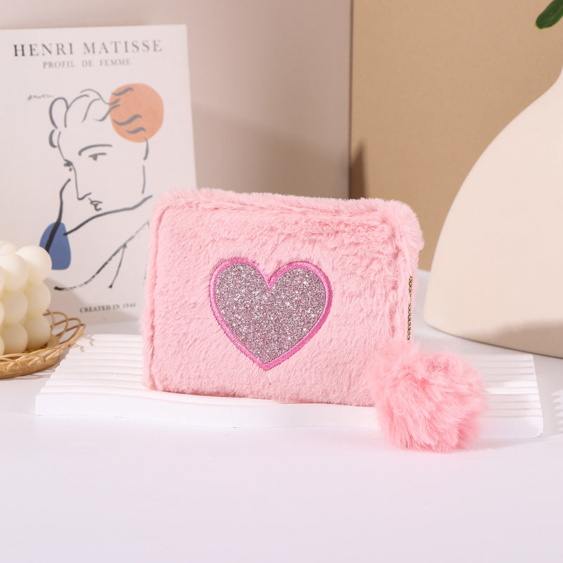 Porte-monnaie en peluche avec fermeture éclair brodée de cœur.