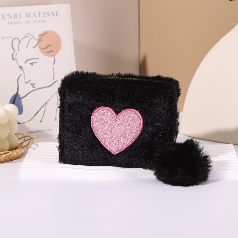 Porte-monnaie en peluche avec fermeture éclair brodée de cœur.